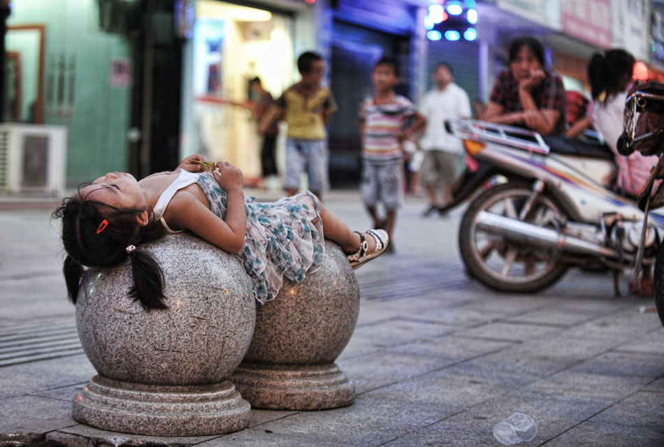 A girl takes a rest at the roadside in Chengbu Miao Autonomous County in central China's Hunan province, July 13, 2013. (Photo/Cheng Tingting)