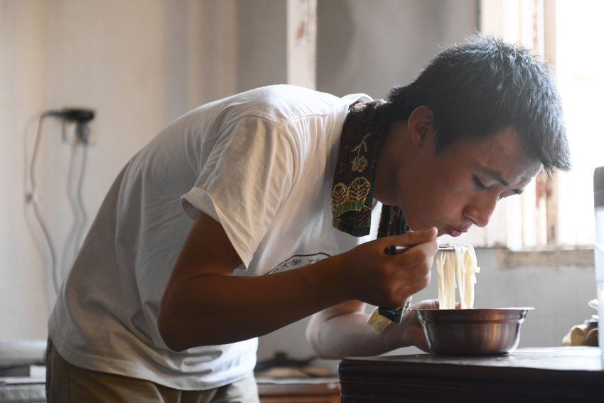 Xue Zei eats noodles in the rented room on July 18. (Xinhua/ Zhang Rui)