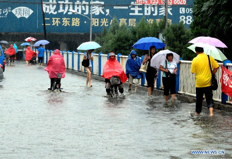 People walk on the waterlogged Shengchan Road in Jinan, capital of east China's Shandong Province, July 23, 2013. A heavy rainfall hit Jinan on Tuesday. (Xinhua/Xu Suhui)
