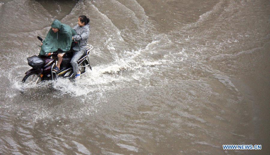 Citizens ride on a flooded road in Liaocheng City, east China's Shandong Province, July 23, 2013. Heavy rainfall hit parts of the province in these two days. (Xinhua/Kong Xiaozheng)