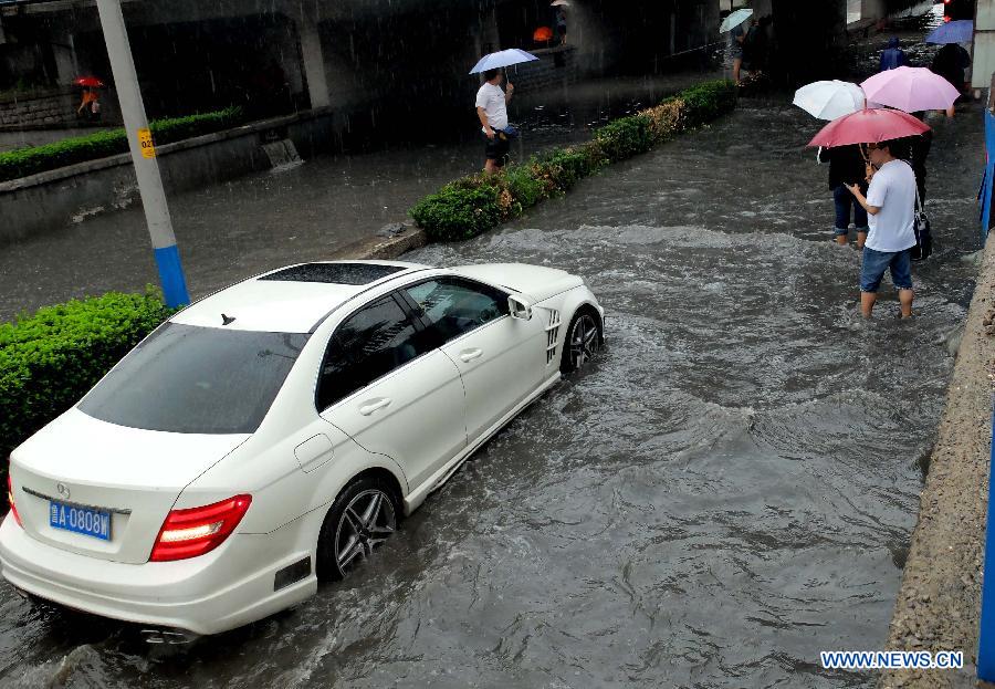 A car is trapped on the waterlogged Shengchan Road in Jinan, capital of east China's Shandong Province, July 23, 2013. A heavy rainfall hit Jinan on Tuesday. (Xinhua/Xu Suhui)