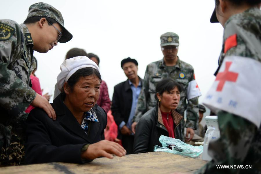 Injured villagers are treated by military health workers in the quake-hit Yongxing Village, Meichuan Township, Minxian County, northwest China's Gansu Province, July 23, 2013. An emergency team of health workers sent by a military hospital in Gansu arrived in Minxian after a 6.6-magnitude earthquake jolted the province on Monday. They have received some 60 severely wounded people. (Xinhua/Jin Liangkuai)