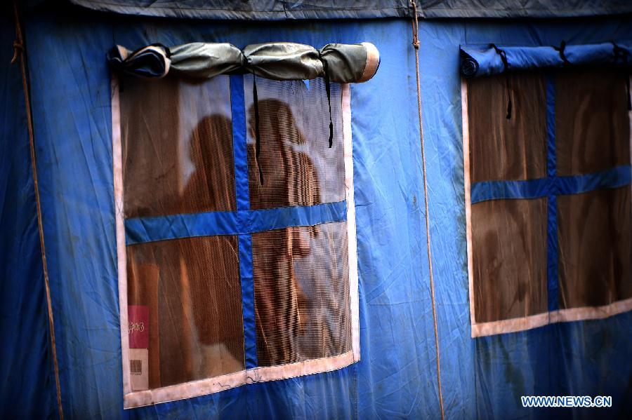 The shadows of a woman and a child are reflected on the window of a tent in quake-hit Yongxing Village of Minxian County, northwest China's Gansu Province, July 24, 2013. The death toll has climbed to 95 in the 6.6-magnitude earthquake which jolted a juncture region of Minxian County and Zhangxian County in Dingxi City Monday morning. (Xinhua/Zhang Meng)