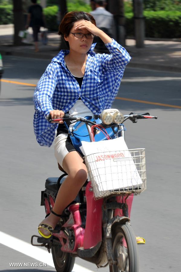 A citizen rides on a road as heat wave hits Shijiazhuang, north China's Hebei Province, July 24, 2013. The highest temperature in some areas of Hebei Province was forecasted to reach 37 degrees Celsius on Wednesday. (Xinhua/Zhu Xudong) 