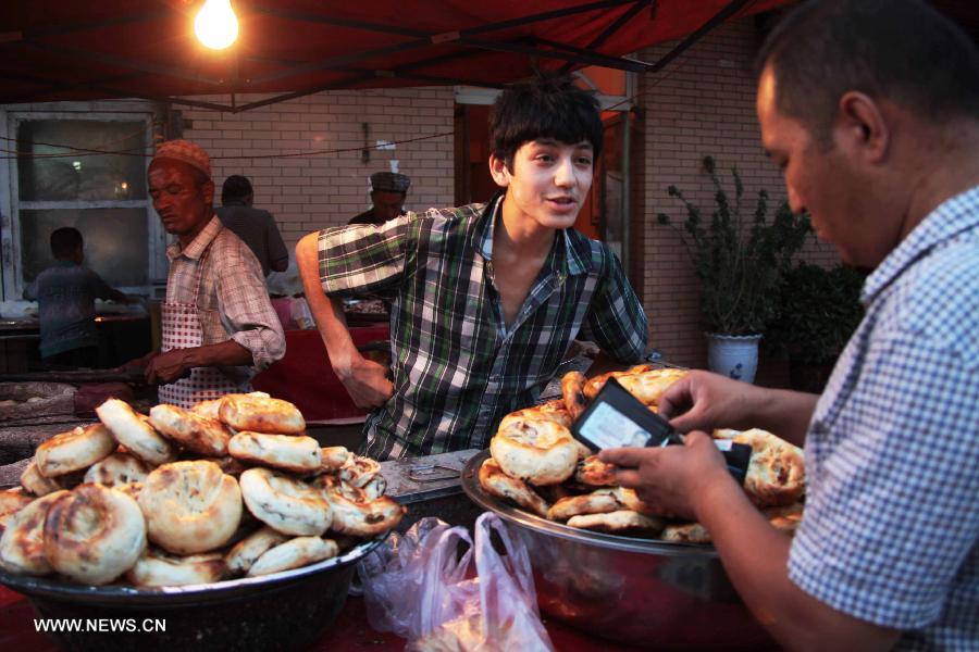 A young man sells baking Nang, a local food, in Kashgar, northwest China's Xinjiang Uygur Autonomous Region, July 24, 2013.(Xinhua/Gao Wenfeng)