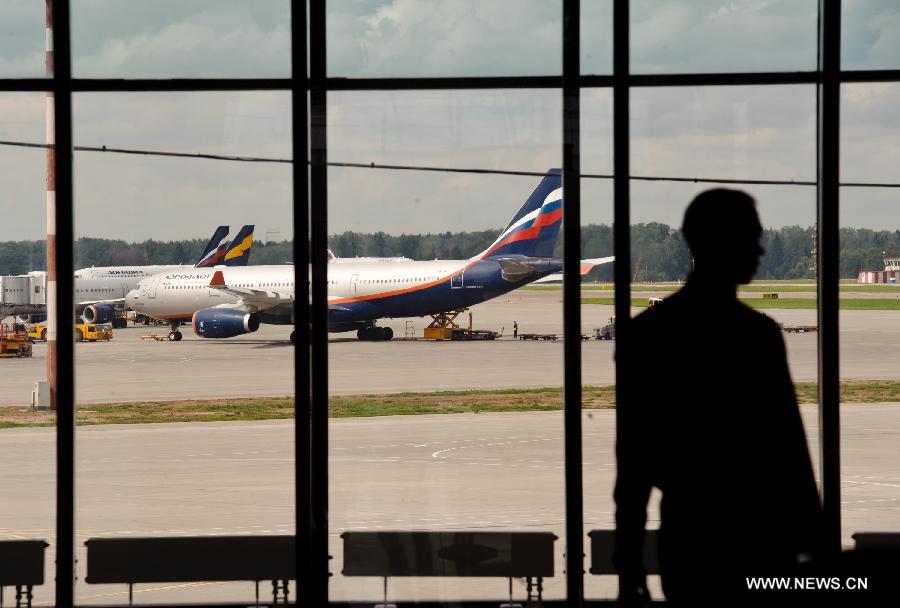 A passenger passes by a window at terminal E of the Sheremetyevo airport in Moscow, Russia, July 24, 2013. A Russian lawyer who has been working on Snowden's behalf has arrived at Moscow's Sheremtyevo Airport, heightening speculations that the U.S. whistleblower may have been granted permission to leave the transit area and enter Russia. (Xinhua/Jiang Kehong)