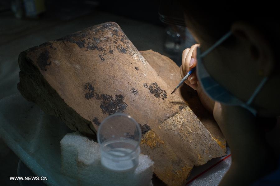An archeological worker preserves original embellishment on a piece of terracotta warrior with special chemical method at the Emperor Qinshihuang's Mausoleum Site Museum in Xi'an, capital of northwest China's Shaanxi Province, July 18, 2013. The 2,200-year-old mausoleum was discovered in Lintong District, 35 km east of Xi'an, in 1974 by peasants who were digging a well. The Chinese terracotta army buried around the mausoleum was one of the greatest archeological finds of modern times. (Xinhua/Xue Yanwen) 