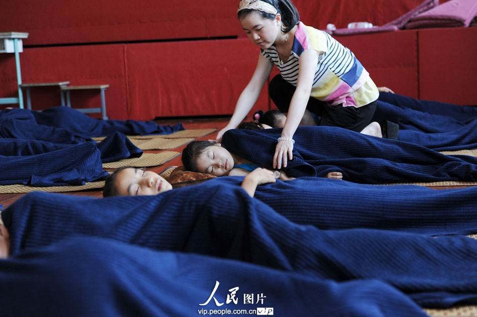 A teacher tucks the children with blankets. Children took a nap at noon in the Dancing Classrooms in the Youth Palace of Yuyao City, east China’s Zhejiang province. (Photo by Chen Binrong/ vip.people.com.cn)