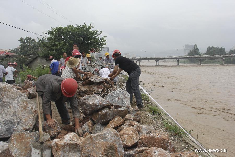 Residents reinforce the riverbank of the Dong River in Chengxian County of Longnan City, northwest China's Gansu Province, July 25, 2013. A torrential rain battered Chengxian County Wednesday night, causing landslips, collapses and traffic disrupted. A total of 1,060 residents have been evacuated by now. (Xinhua/Liu Min)