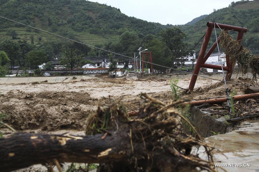A bridge linking Baiwan Village and outside is swept away by flood in Chengxian County of Longnan City, northwest China's Gansu Province, July 25, 2013. A torrential rain battered Chengxian County Wednesday night, causing landslips, collapses and traffic disrupted. A total of 1,060 residents have been evacuated by now. (Xinhua/Liu Min) 