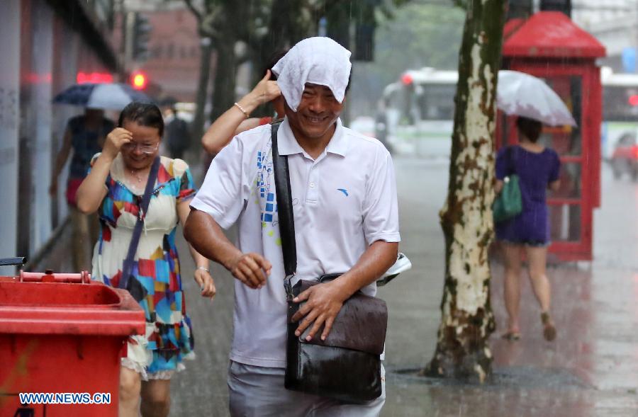 Residents walk in rain on Nanjing Road, east China' Shanghai, July 26, 2013. A rainstorm hit Shanghai Friday afternoon, bringing coolness to the scorching weather. (Xinhua/Yang Shichao)