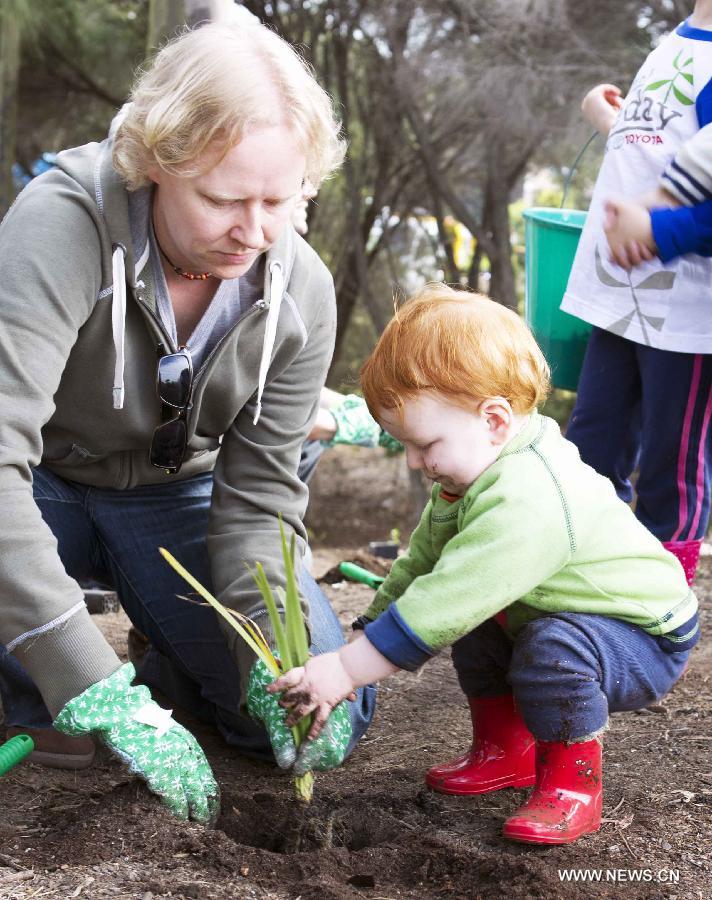 A mother teaches her daughter to plant at the Sydney Park in Sydney, Australia, on July 28, 2013, during the Australia Planet Ark National Tree Day event. Since the first Planet Ark National Tree Day in 1996, more than three million participants have planted around 20 million trees and shrubs in Australia. (Xinhua/Jin Linpeng)