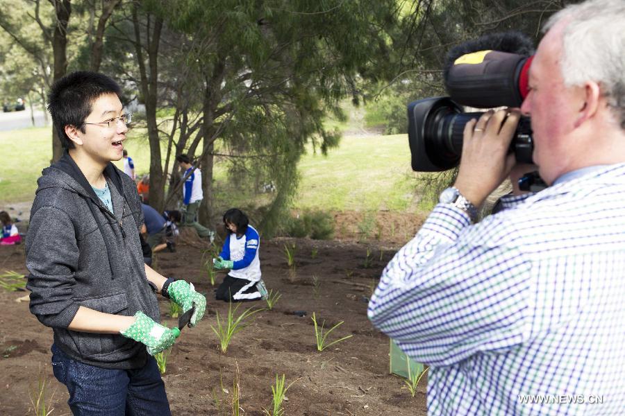 A student speaks for an interview at the Sydney Park in Sydney, Australia, on July 28, 2013, during the Australia Planet Ark National Tree Day event. Since the first Planet Ark National Tree Day in 1996, more than three million participants have planted around 20 million trees and shrubs in Australia. (Xinhua/Jin Linpeng)