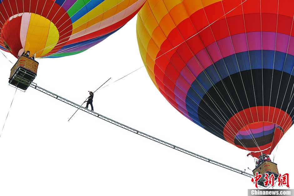 Askar, 40, from Xinjiang, has set a new world record after walking on a tightrope between two moving balloons at high altitude in Shilin, southwest China’s Yunan province on July 30, 2013. He has set World Guinness records for five times. With the help of a steel beam with a diameter of 50 millimeters Askar covered a distance of 18 meters in the air on the rope. (Photo by Ren Dong/ Chinanews.com)