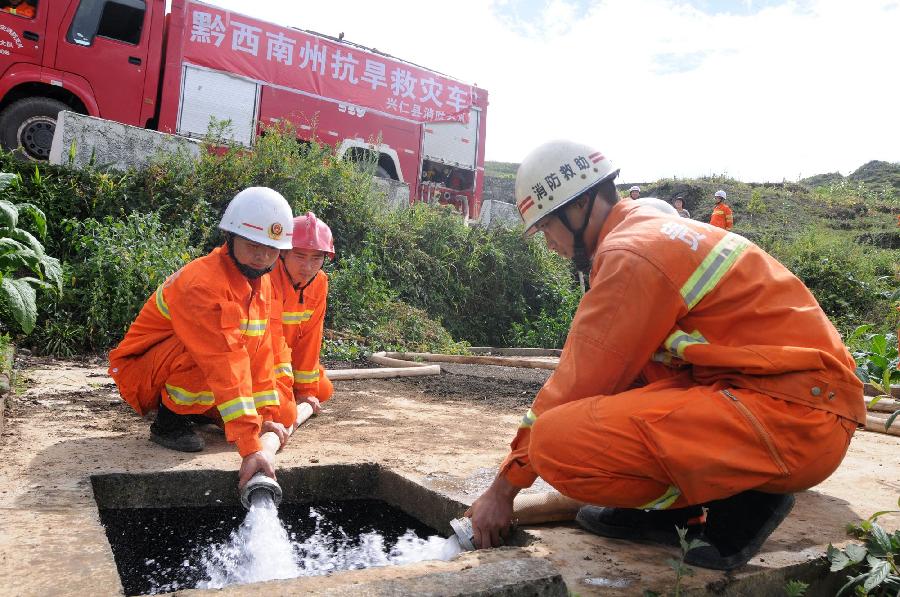 Fire fighters supply water for people living in drought areas in Changtian Township, Zhenfeng County of southwest China's Guizhou Province, July 29, 2013. Due to little rainfall and high temperature, 38 counties in Guizhou Province faced with serious drought in recent days. (Xinhua/Liu Yongsong)
