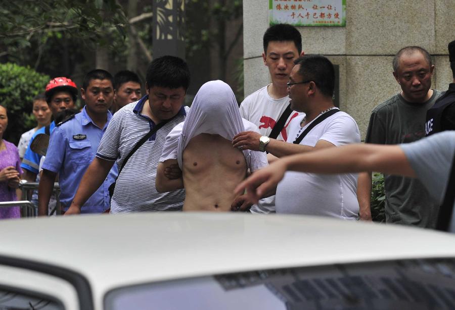 A suspect is arrested in the Chenghua District of Chengdu, capital of southwest China's Sichuan Province, July 31, 2013. A gun fight took place as drug dealers resisted arrest from the police. One suspect jumped from a building and was killed while another two were arrested. (Xinhua/Xue Yubin)