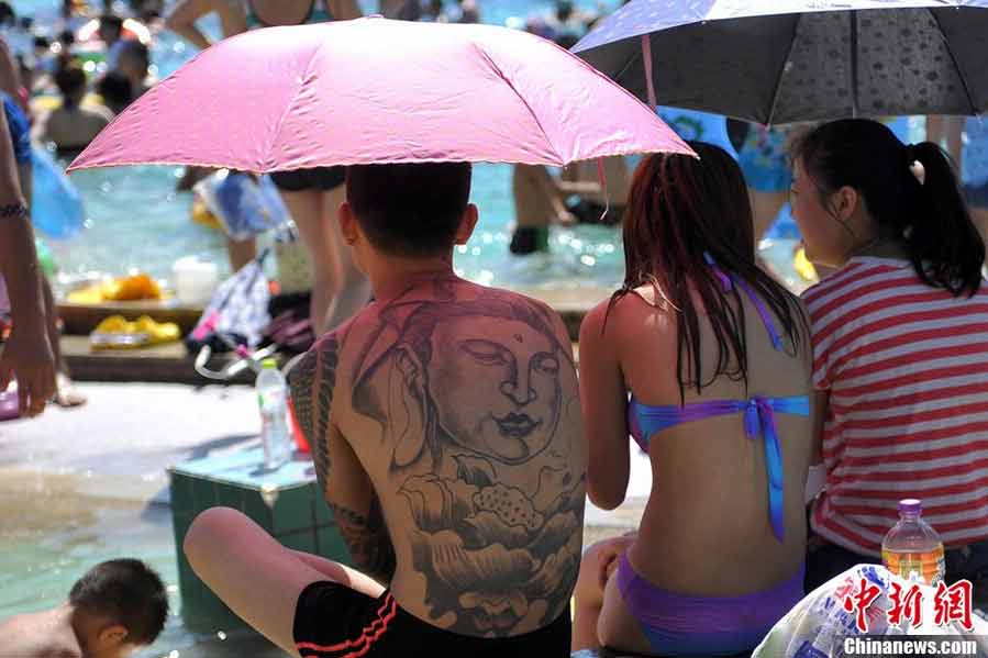 Tourists swarm to the bathing beach in Beijing's Chaoyang Park to escape the stifling heat on July 28, 2013. On the same day, the city's weather authorities issued this summer's second orange high-temperature alert. (Chinanews.com)
