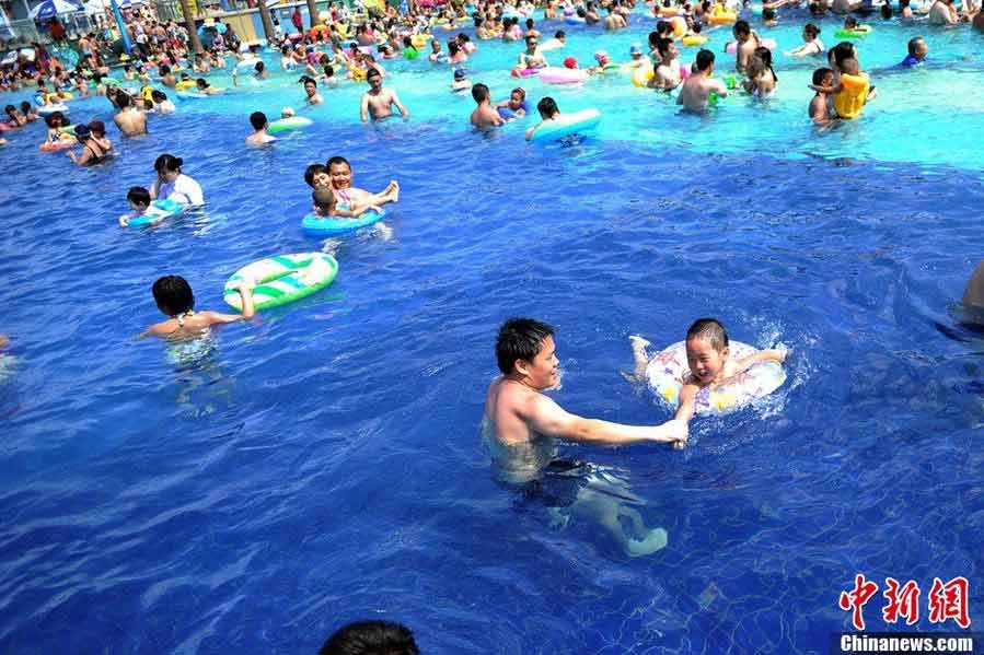 Tourists swarm to the bathing beach in Beijing's Chaoyang Park to escape the stifling heat on July 28, 2013. On the same day, the city's weather authorities issued this summer's second orange high-temperature alert. (Chinanews.com)