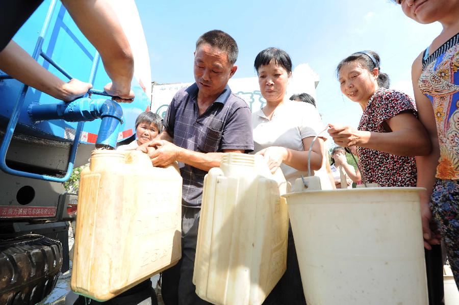 Local residents get water delivered by government in the Jinba Village of Jinsha County, southwest China's Guizhou Province, July 31, 2013. Lingering droughts in Guizhou have affected more than 12 million people. Over 2 million people lack adequate supplies of drinking water, and a total of 847,300 hectares of farmland is damaged by the drought. (Xinhua/Yang Ying)