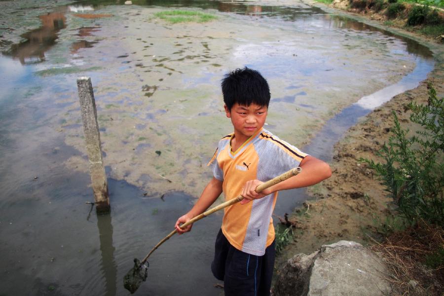 A boy goes fishing in a nearly-dried pond in Jiuchang Town of Xiuwen County, southwest China's Guizhou Province, July 31, 2013. Lingering droughts in Guizhou have affected more than 12 million people. Over 2 million people lack adequate supplies of drinking water, and a total of 847,300 hectares of farmland is damaged by the drought. (Xinhua/Liu Xu)