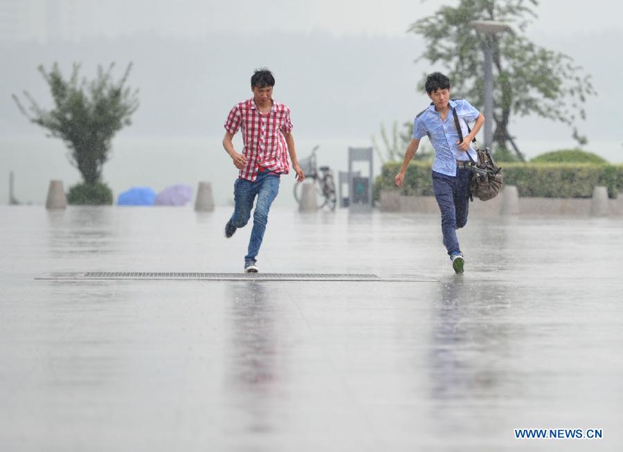Citizens run in the rain in Nanjing, capital of east China's Jiangsu Province, July 31, 2013. An artificial precipitation brought coolness to citizens in Nanjing. (Xinhua/Lang Congliu)