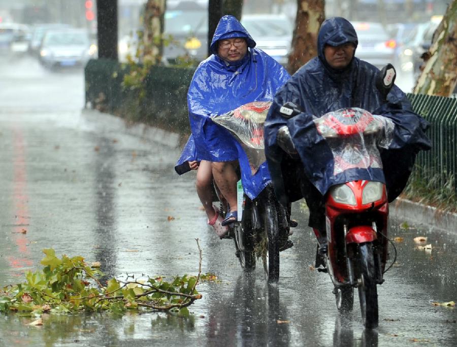 Local residents ride in rain in Hangzhou, capital of east China's Zhejiang Province, July 31, 2013. A thunder shower on Wednesday brought cool to Hangzhou, a city that has experienced six days of temperature over 40 degrees Celsius since July 24. (Xinhua/Wang Dingchang)